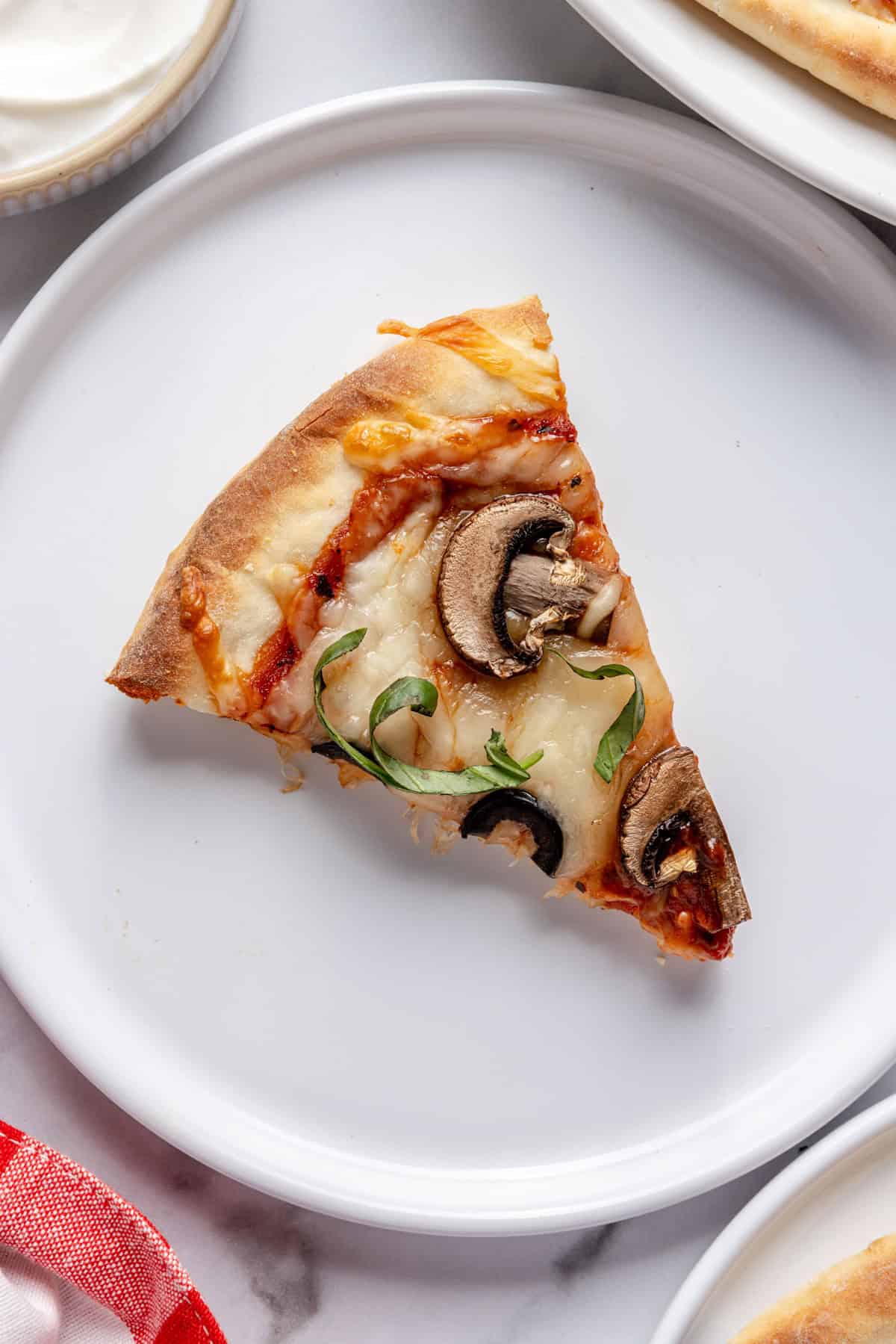 A slices of greek yogurt pizza dough pizza with mushrooms and olives on a plate.