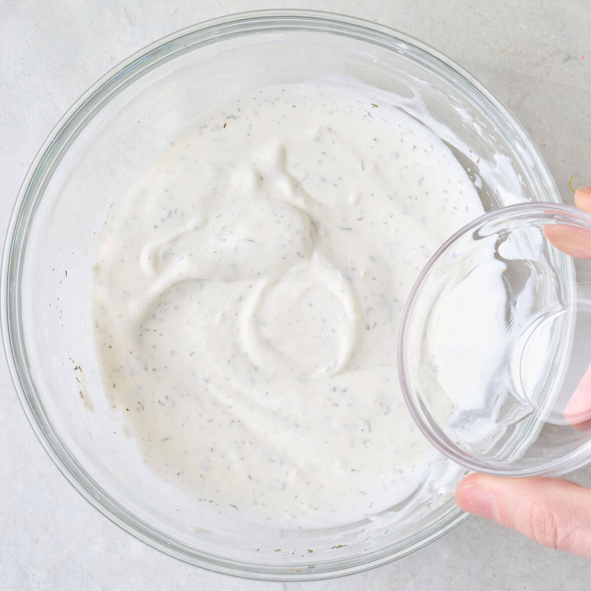 Pouring in water to sauce to thin.