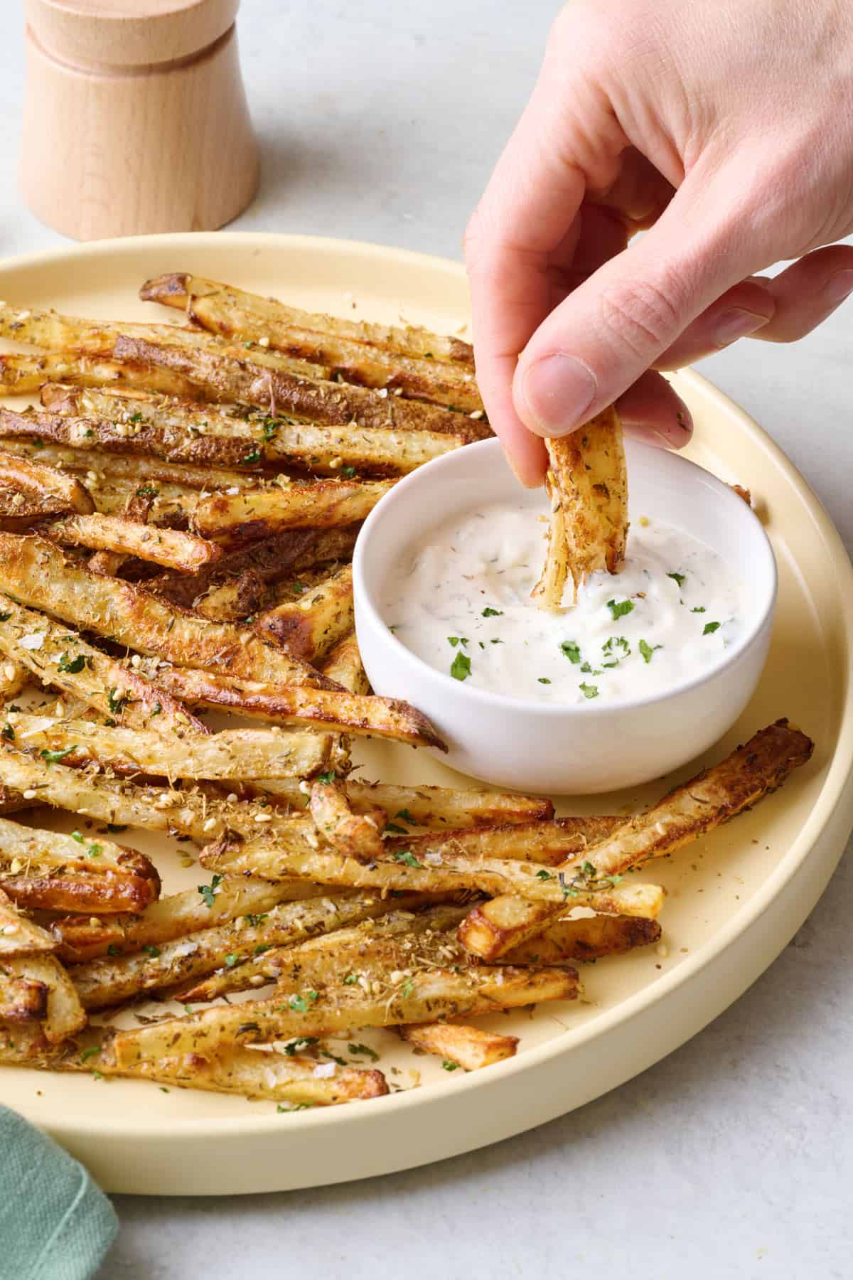 Seasoned fries being dipped into homemade greek yogurt sauce.