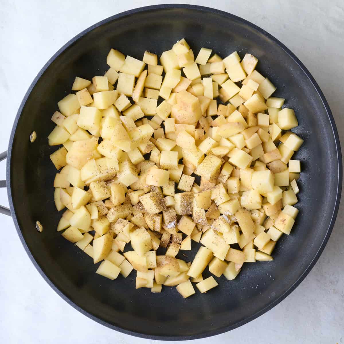 Diced potatoes, salt and pepper in an oiled skillet.