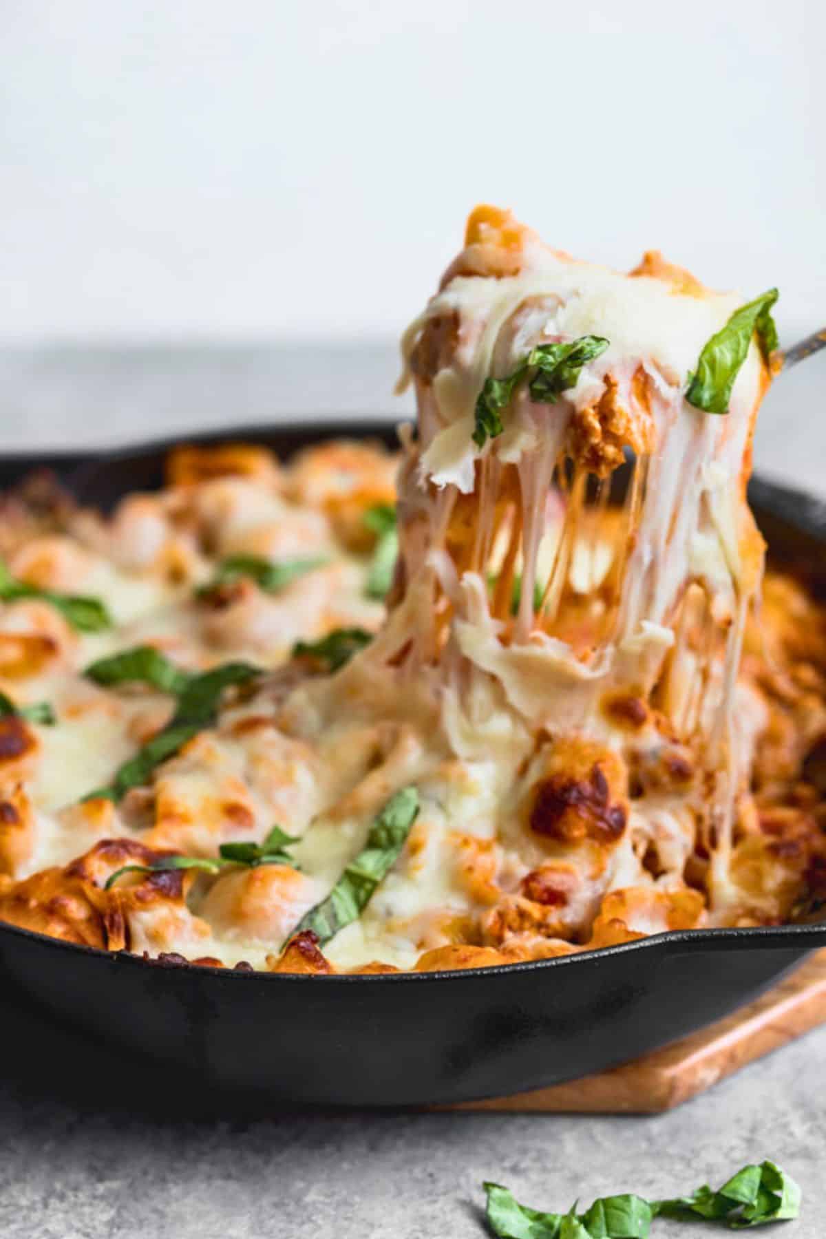 Spoon lifting up a cheesy serving of baked pasta with ground turkey.