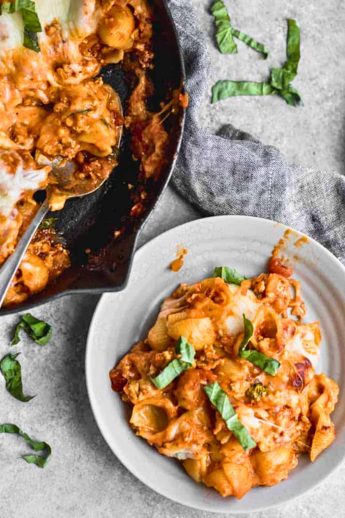 Baked pasta made with ground turkey on a plate with skillet nearby.