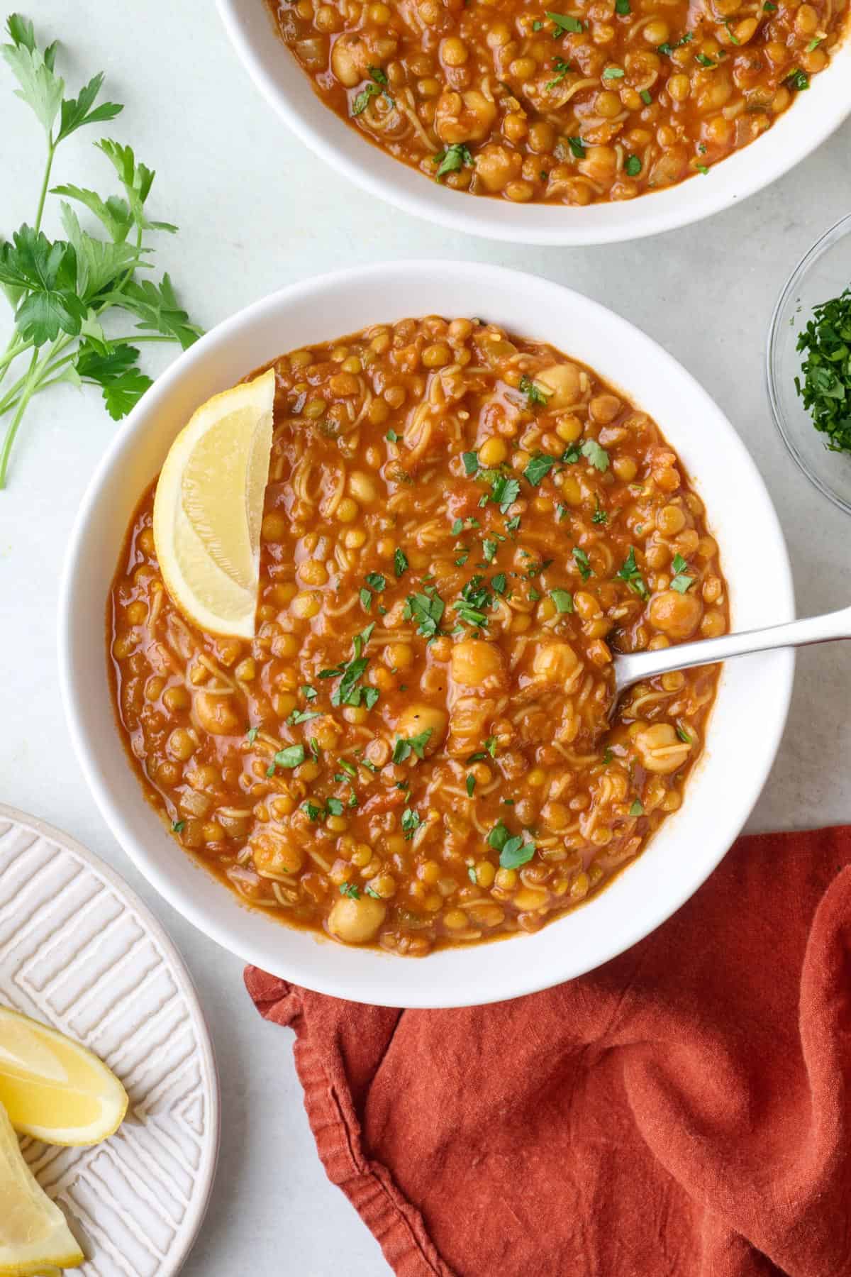 Morcoccan harira soup recipe in a bowl garnished with a lemon wedge and fresh parsley.