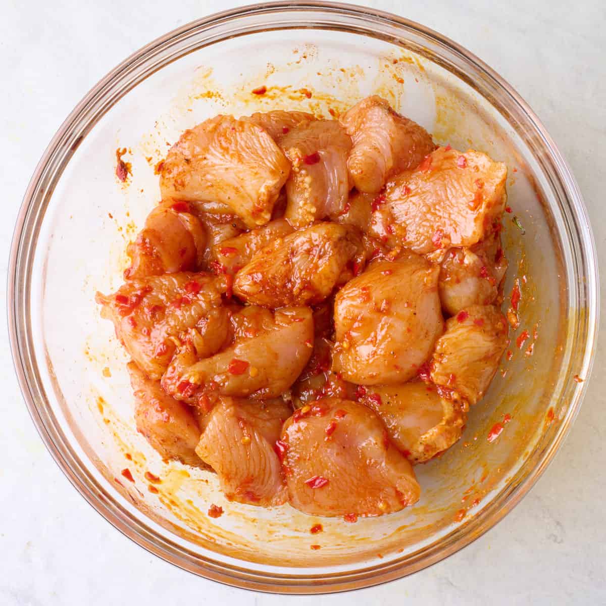 Chicken pieces coated in oil and spices in a bowl.