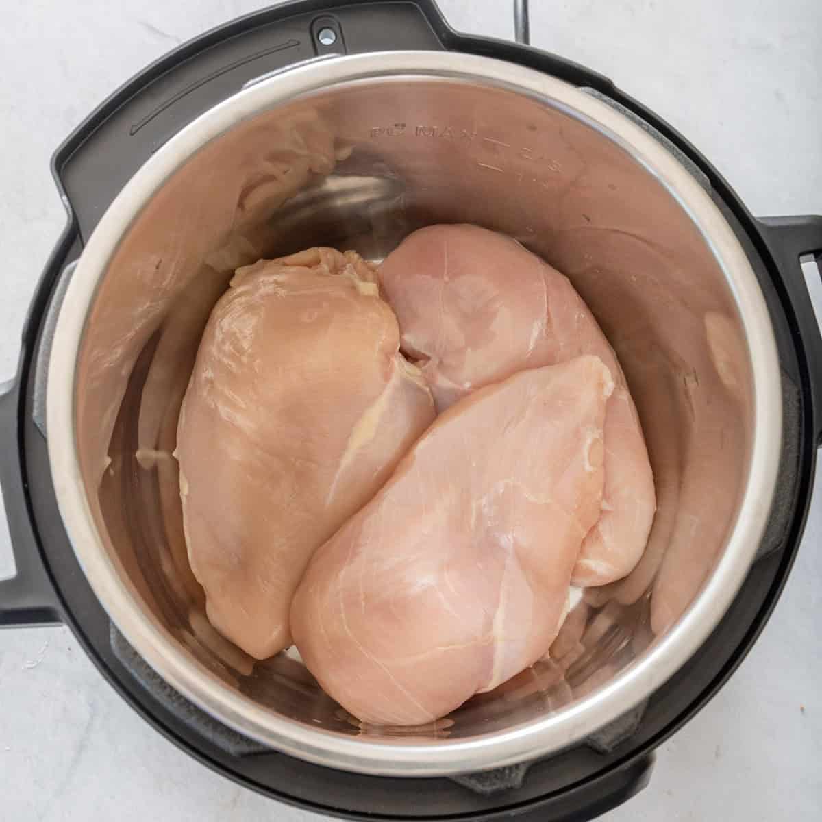 Raw whole chicken breasts in an instant pot.