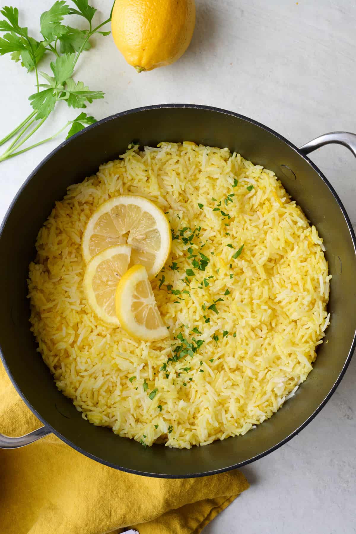 Lemon rice in pot after fluffing with fresh lemon and parsley around.