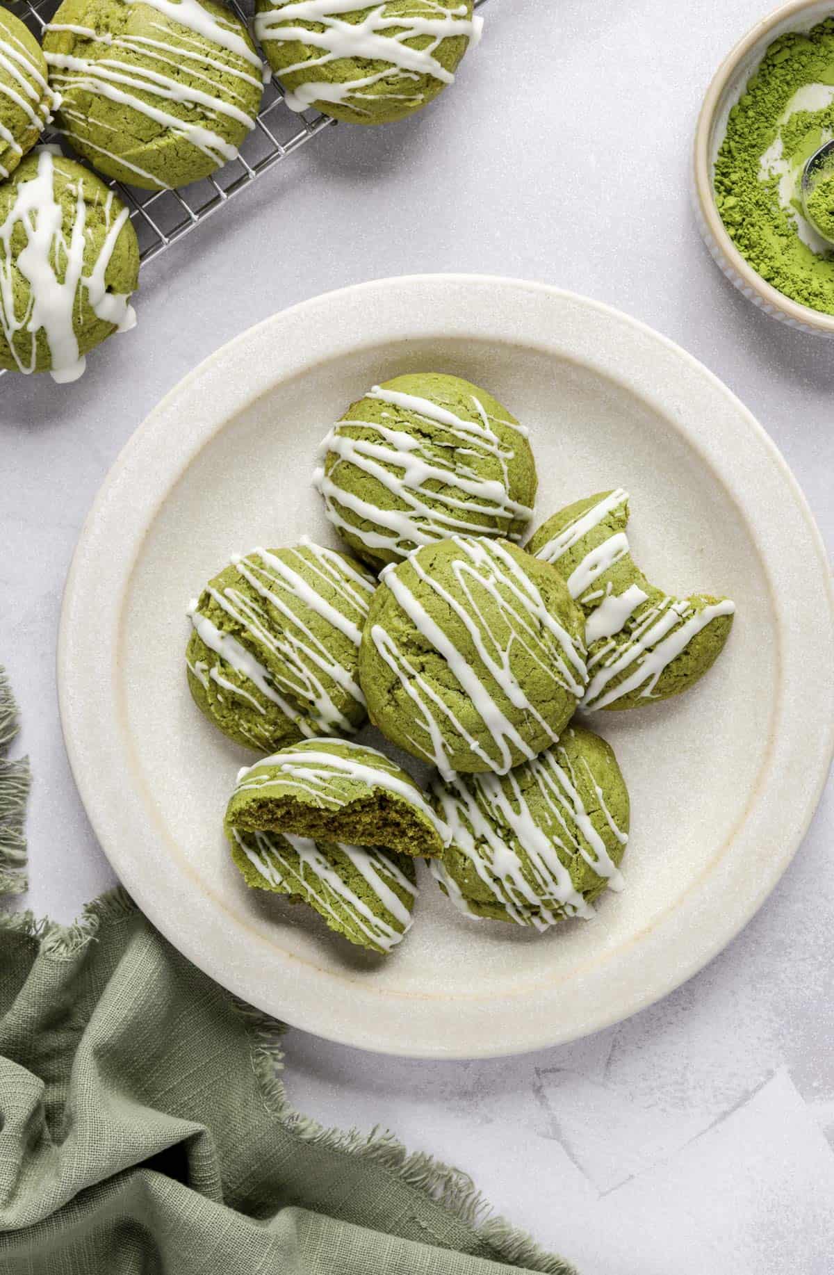 Matcha cookies with white chocolate drizzle on a plate.