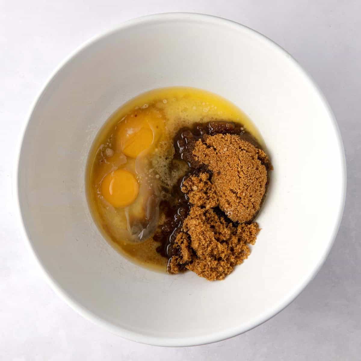 Eggs, melted butter and brown sugar in a bowl.