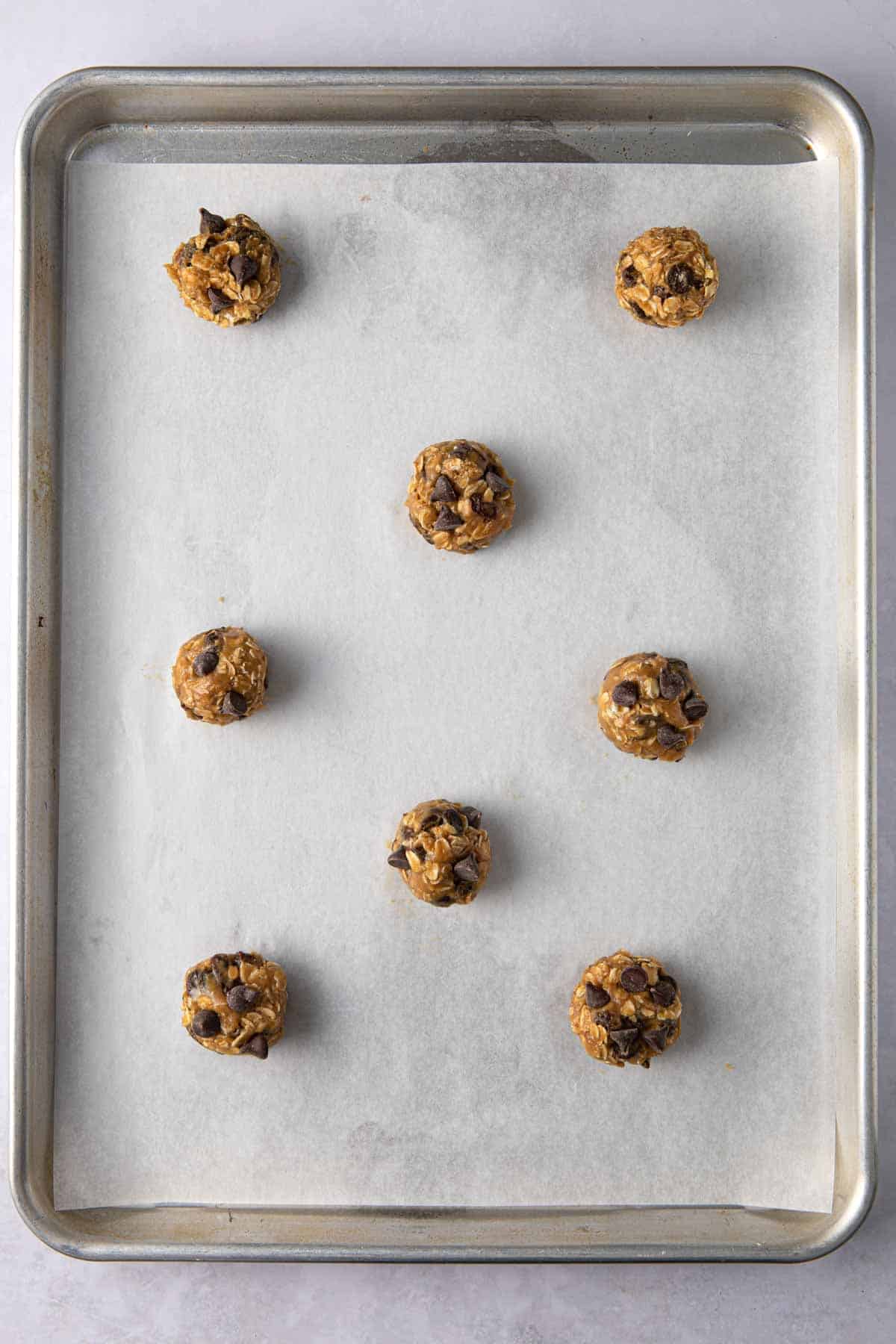 Cookie dough balls on a parchment line sheet pan.