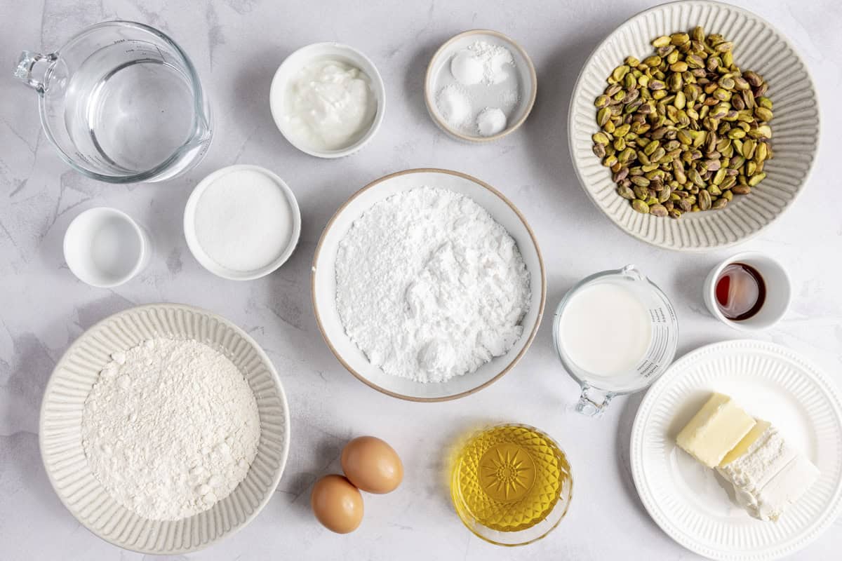 Ingredients for recipe: salt, sugar, yogurt, flour, baking powder, baking soda, pistachios, milk, eggs, oil, vanilla, cream cheese and butter, and powdered sugar.