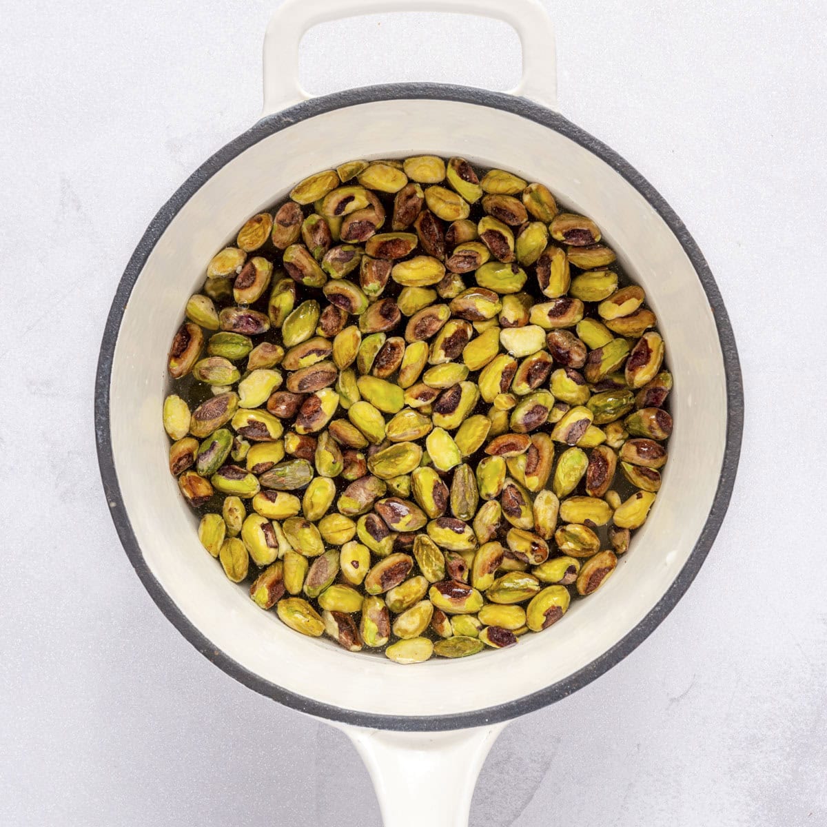 Pistachios in a small pot of water.