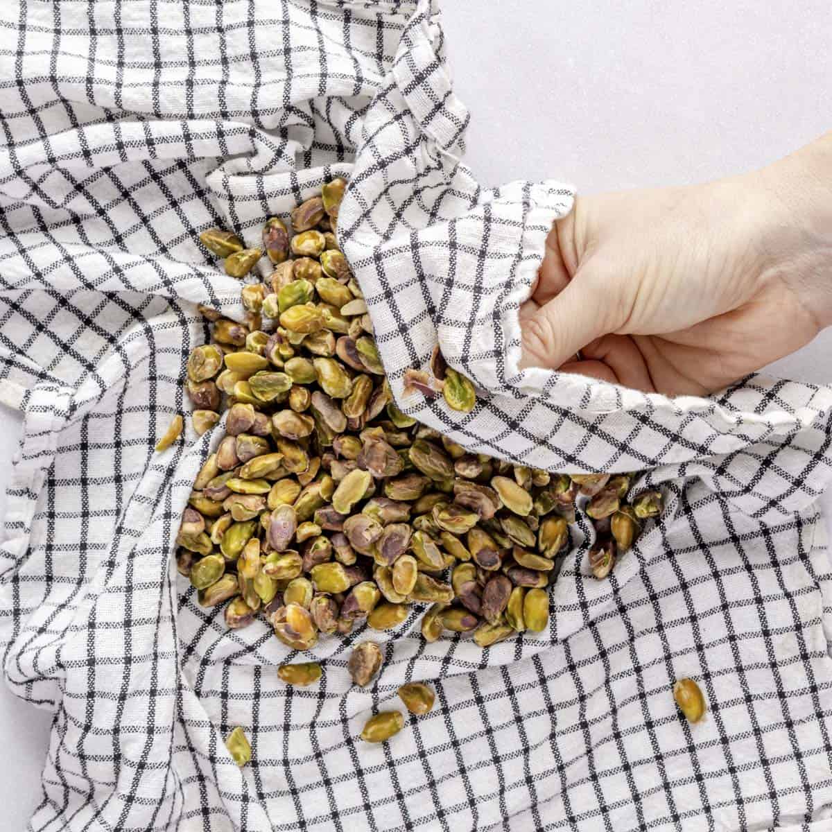 Rubbing soaked pistachios with towel to remove skins.