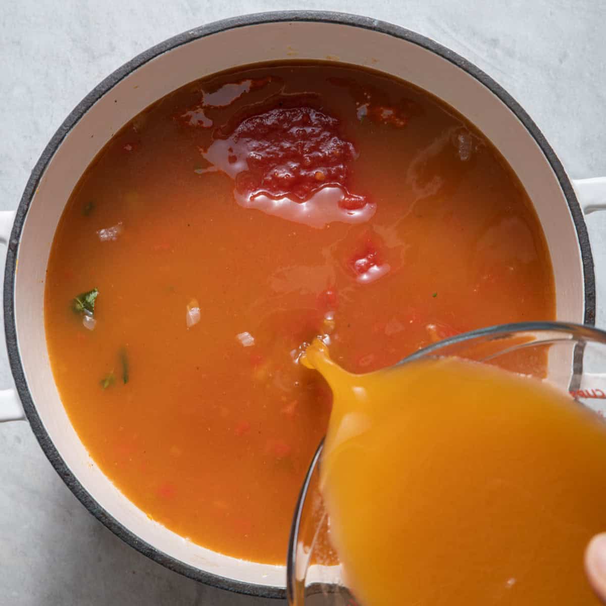 Pouring broth into soup pot.