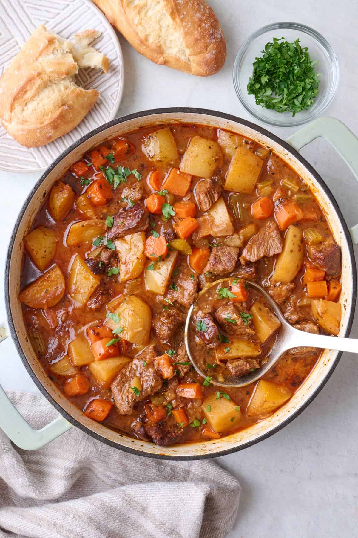 Stovetop beef stew in pot with carrots, potatoes, celery and beef.