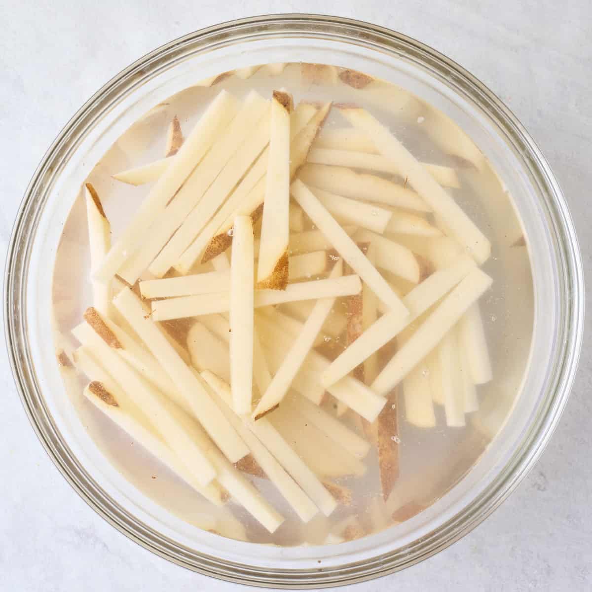 Potato sticks in a bowl of water.