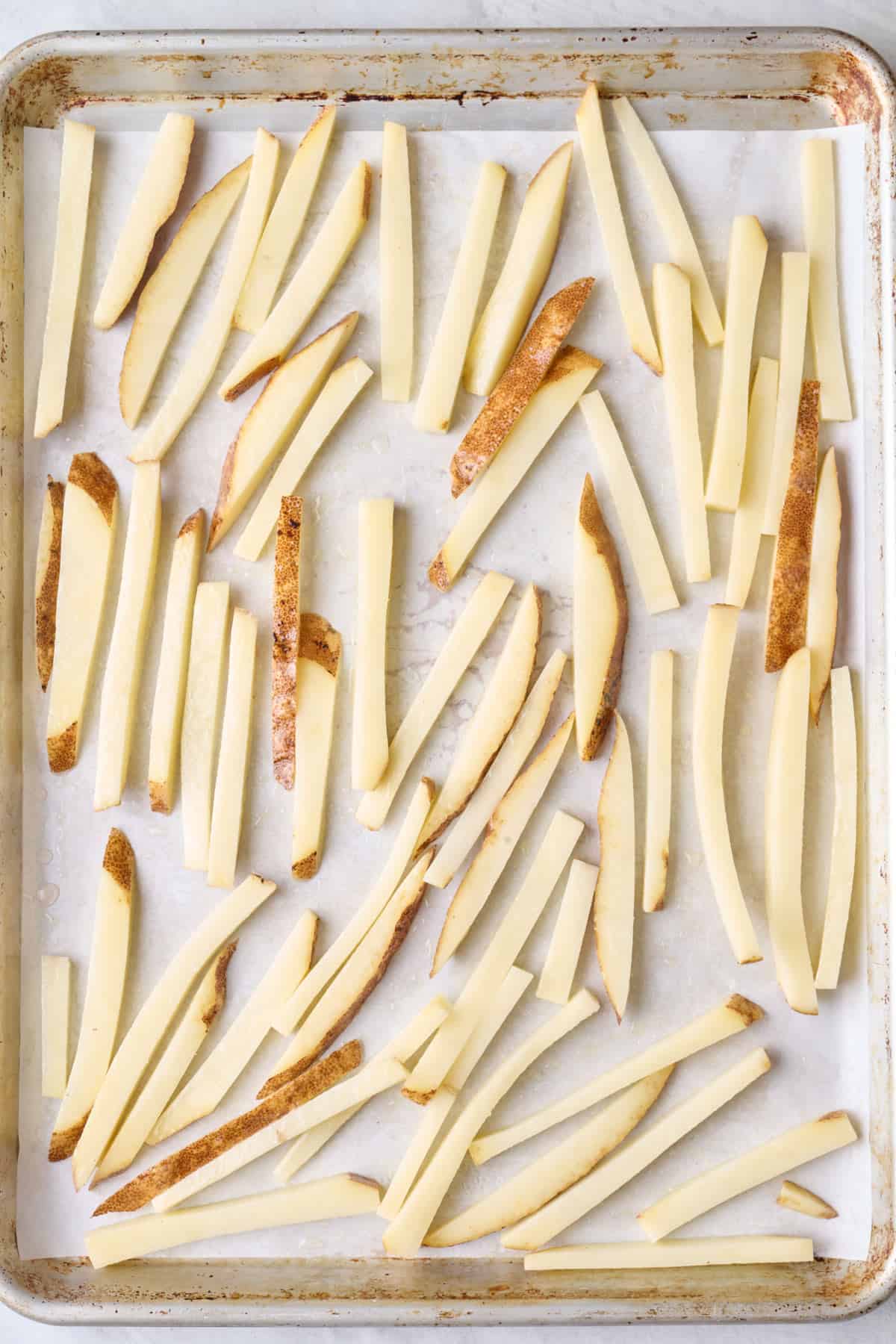 Potatoes after soaking and drying on a baking sheet with oil and salt.