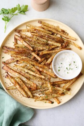 Zaatar fries on a round plate with a side of tahini yogurt sauce.