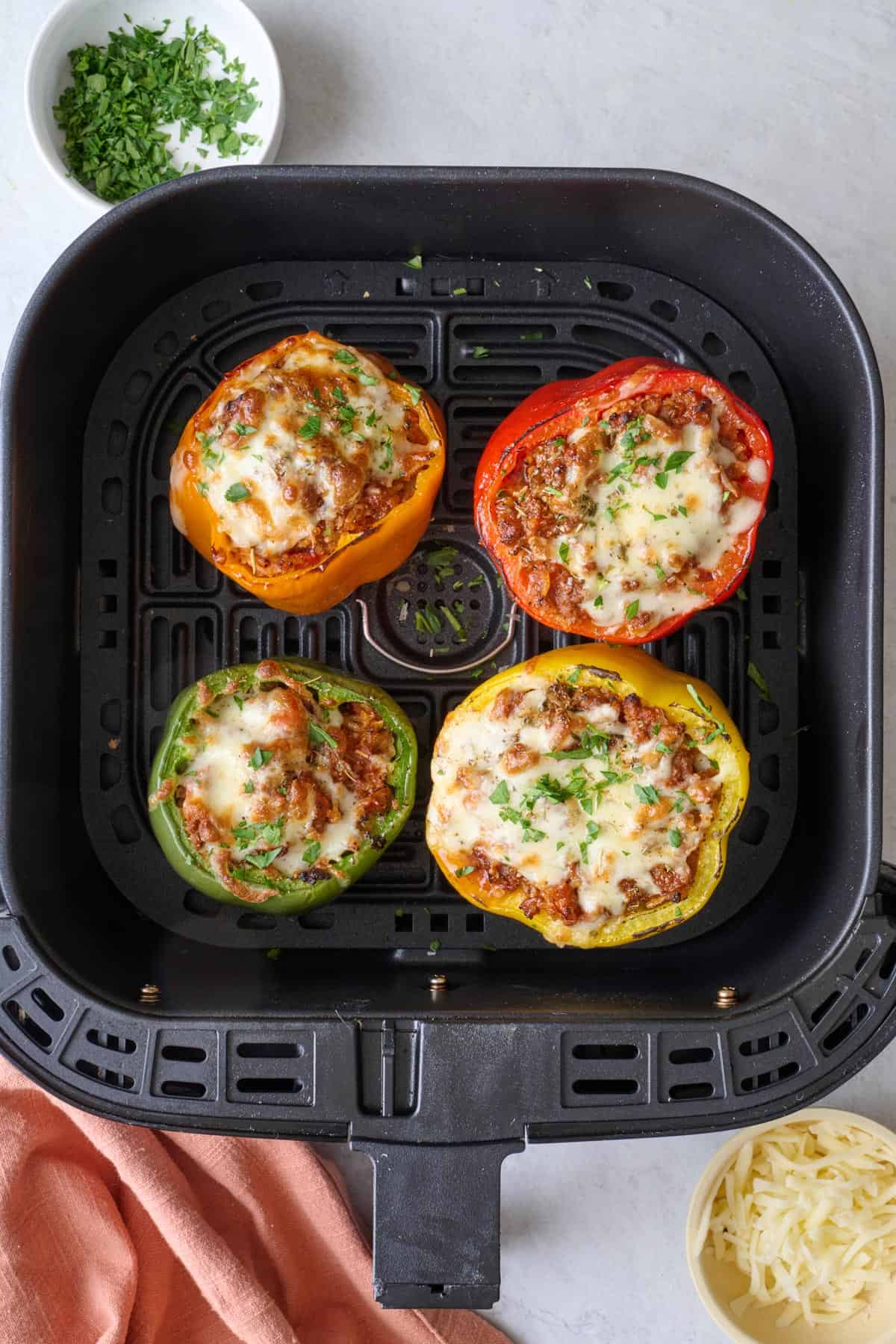 Air fryer stuffed peppers in an air fryer basket garnished with fresh chopped parsley.