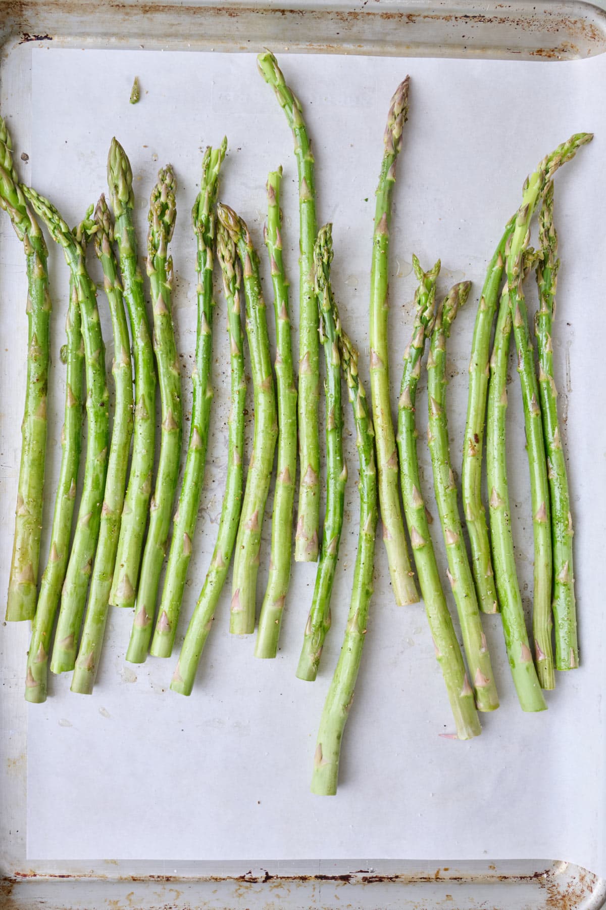 Trimmed asparagus on a sheet pan before baking.