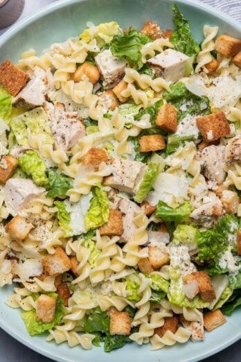 Bowl with all the ingredients and dressing getting poured on top.