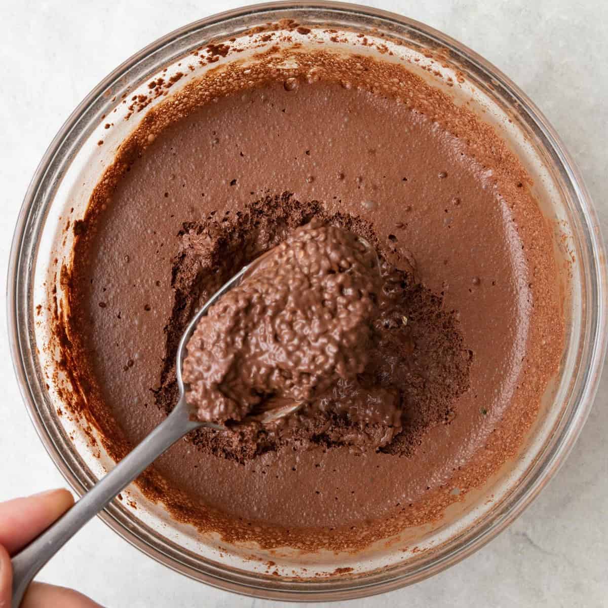 Spoon lifting up some of the chilled chia pudding to show thickened consistency.