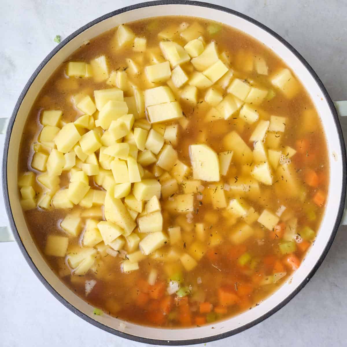 Potatoes and broth added to pot.