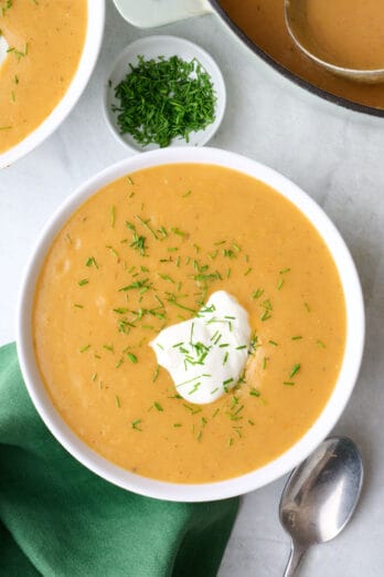 Creamy potato soup in a bowl garnished with sour cream and chives.