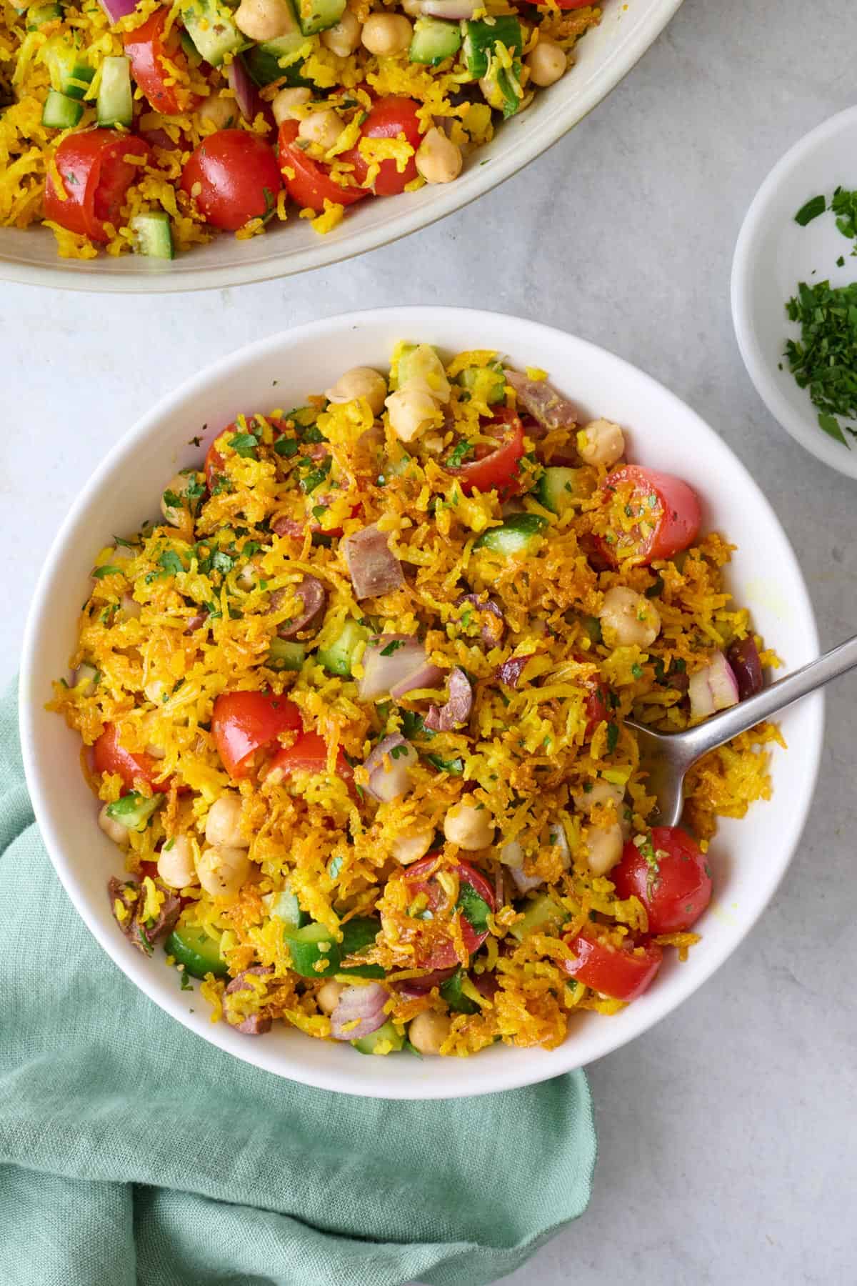 Serving of crispy rice salad with cucumbers, tomatoes, onion, olives, and chickpeas in a bowl.