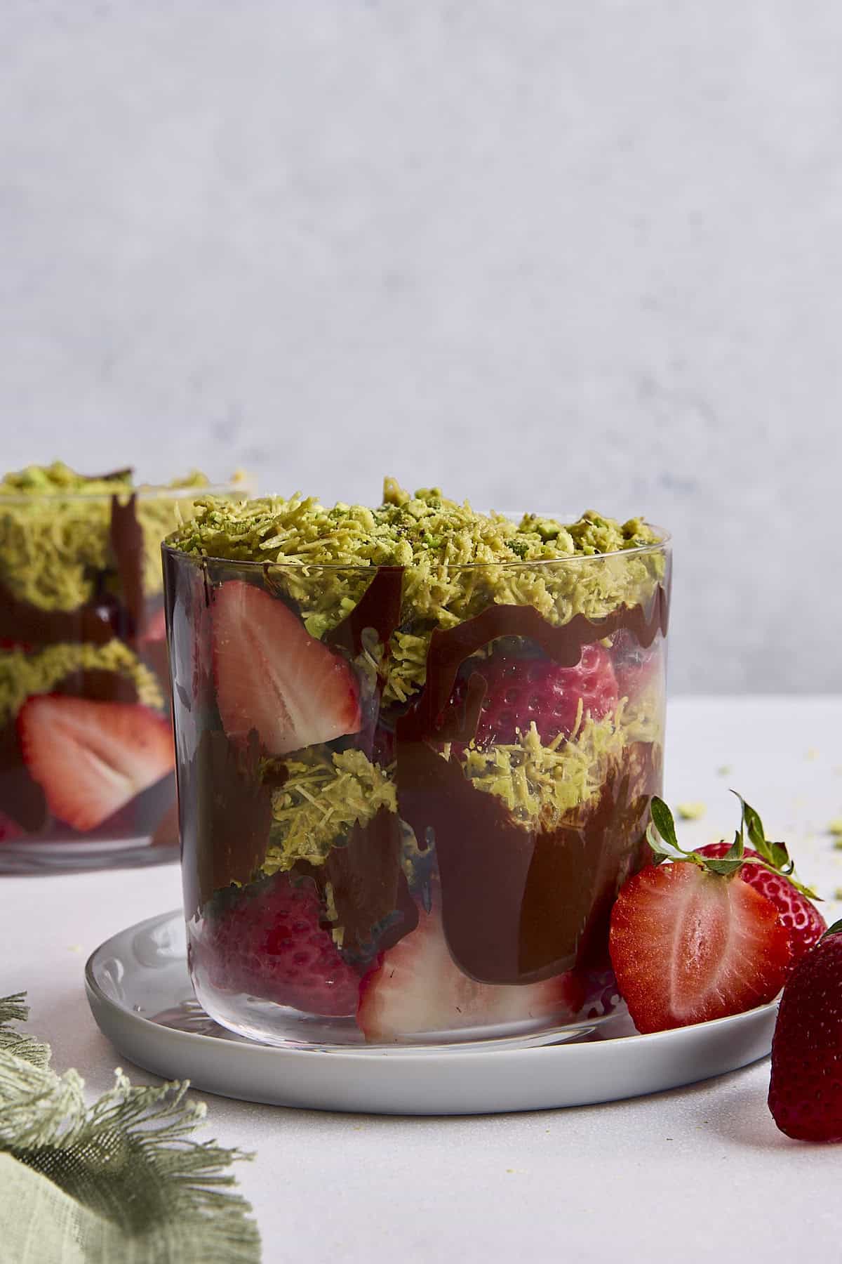 Dubai chocolate strawberries in a glass dessert cup with layers of fresh strawberries, chocolate, and a pistachio and shredded phyllo filling.