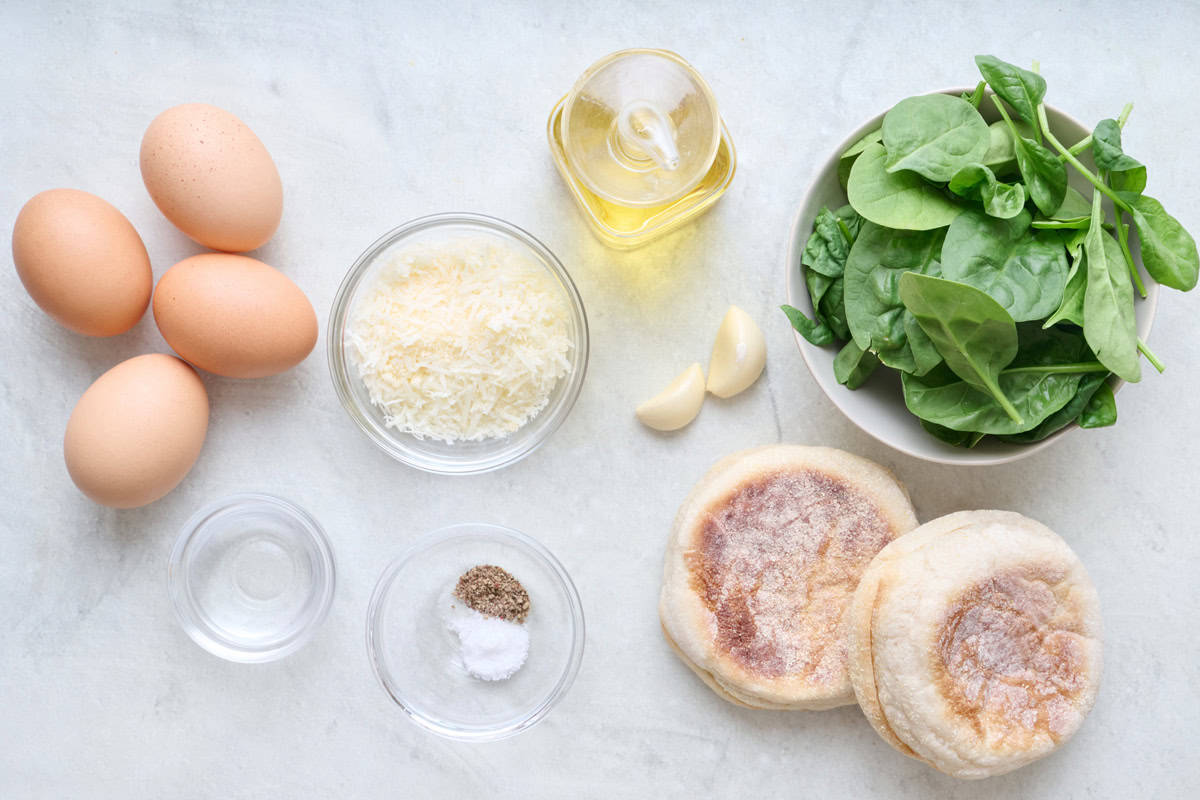 Ingredients for recipe: eggs, parmesan, oil, spinach, garlic, salt and pepper, vinegar and english muffins.