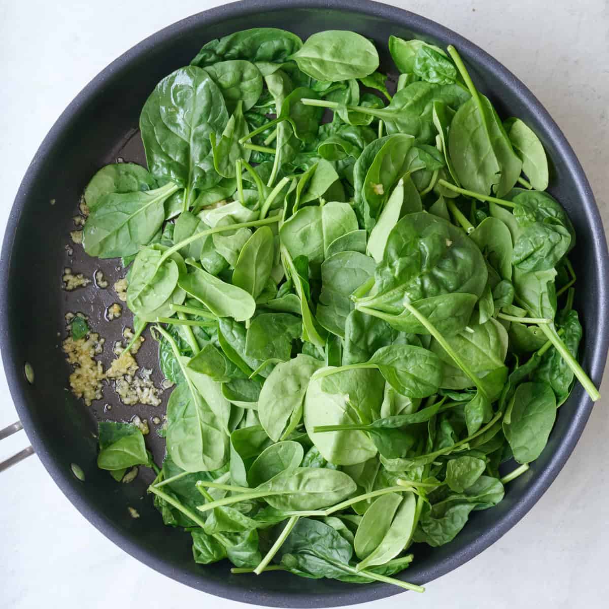 Fresh spinach added to skillet.