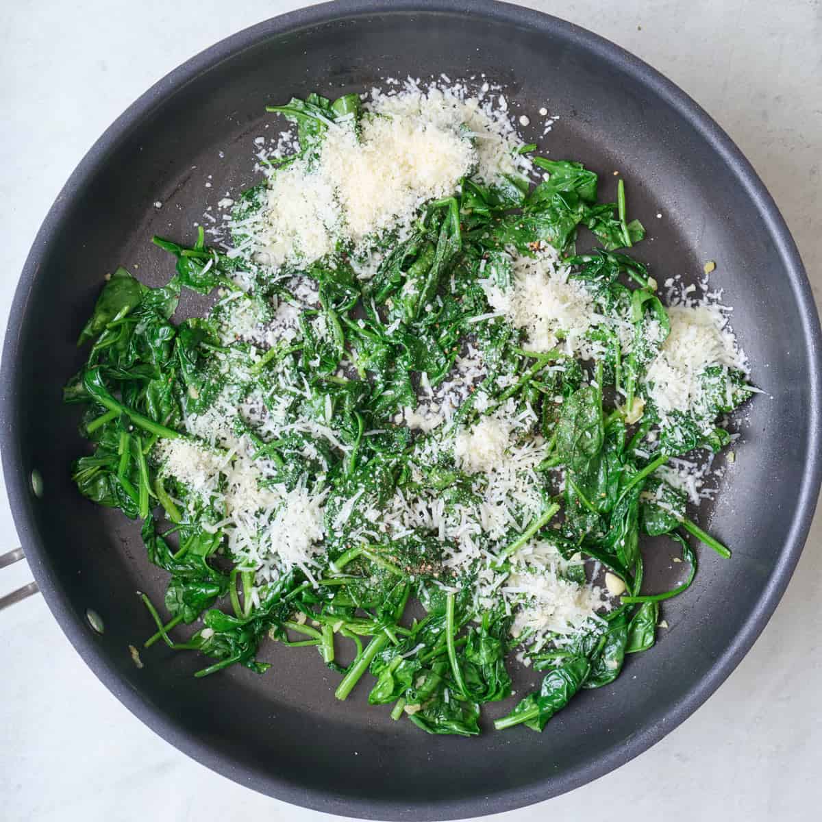 Spinach after cooking in pan with parmesan added.