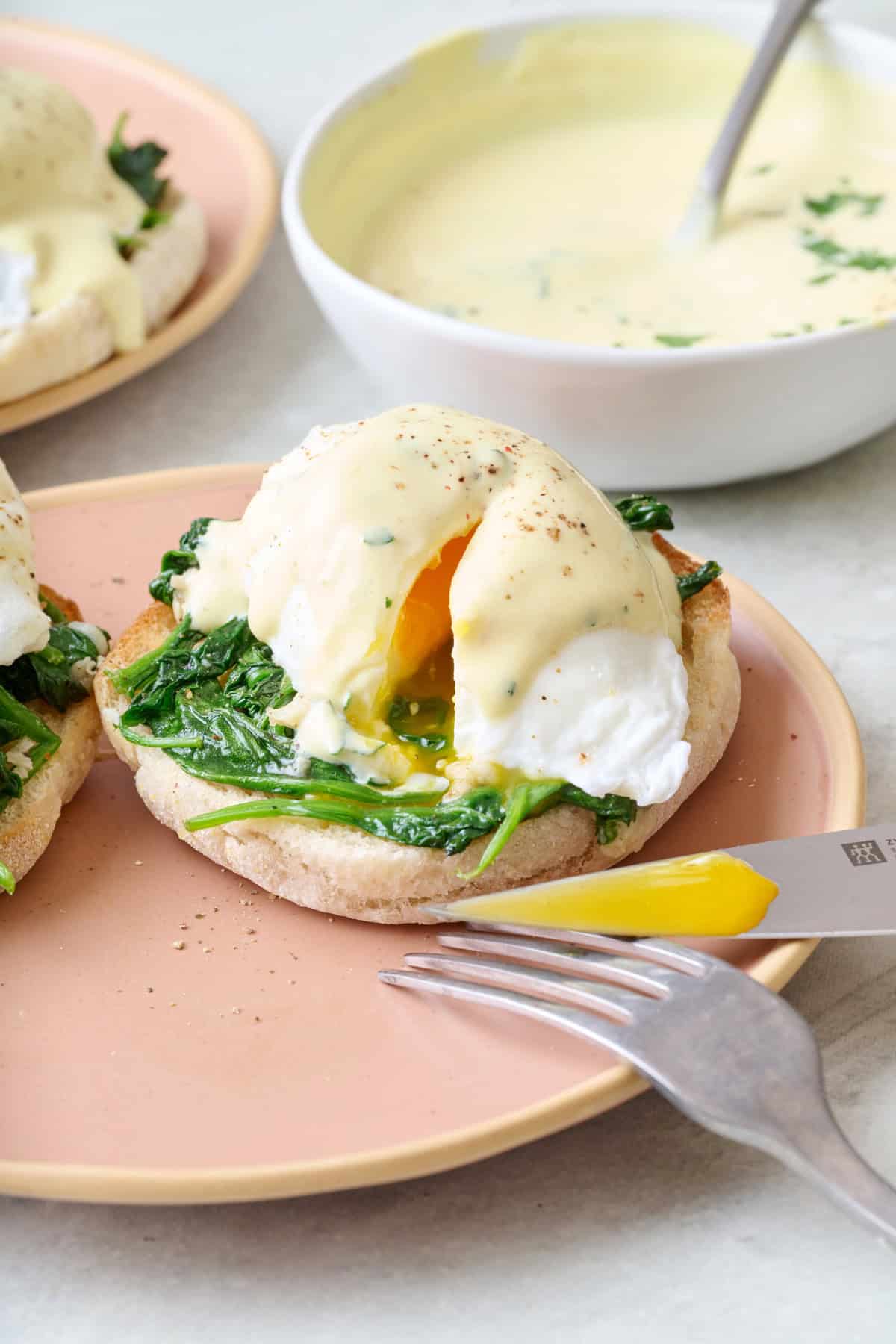 Eggs Florentine on a plate with egg split open to show runny yolk.
