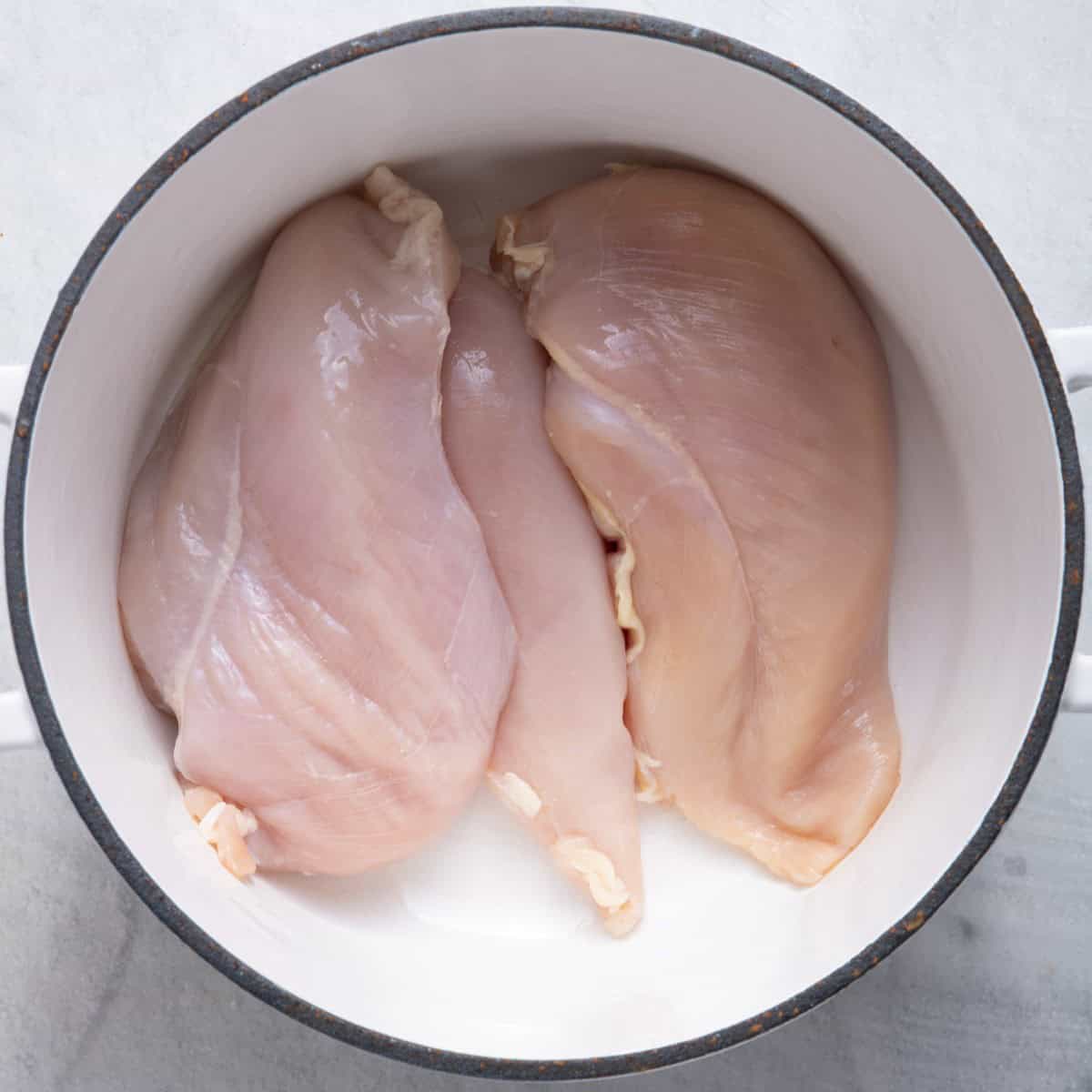 Three large chicken breasts in a pot.