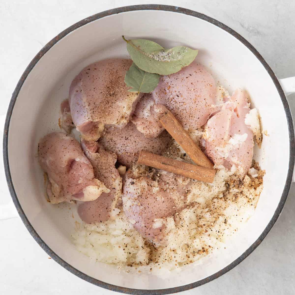 Chicken thighs, onion, cinnamon sticks, bay leaves, added in a large stockpot without water before cooking.