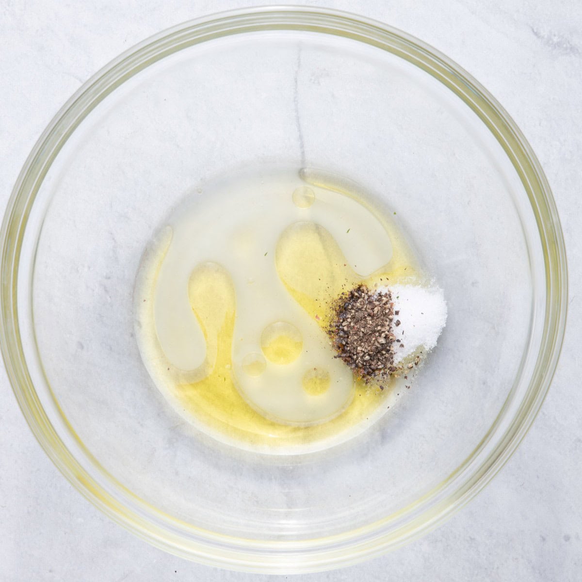Oil, lemon juice, salt and pepper in a bowl.