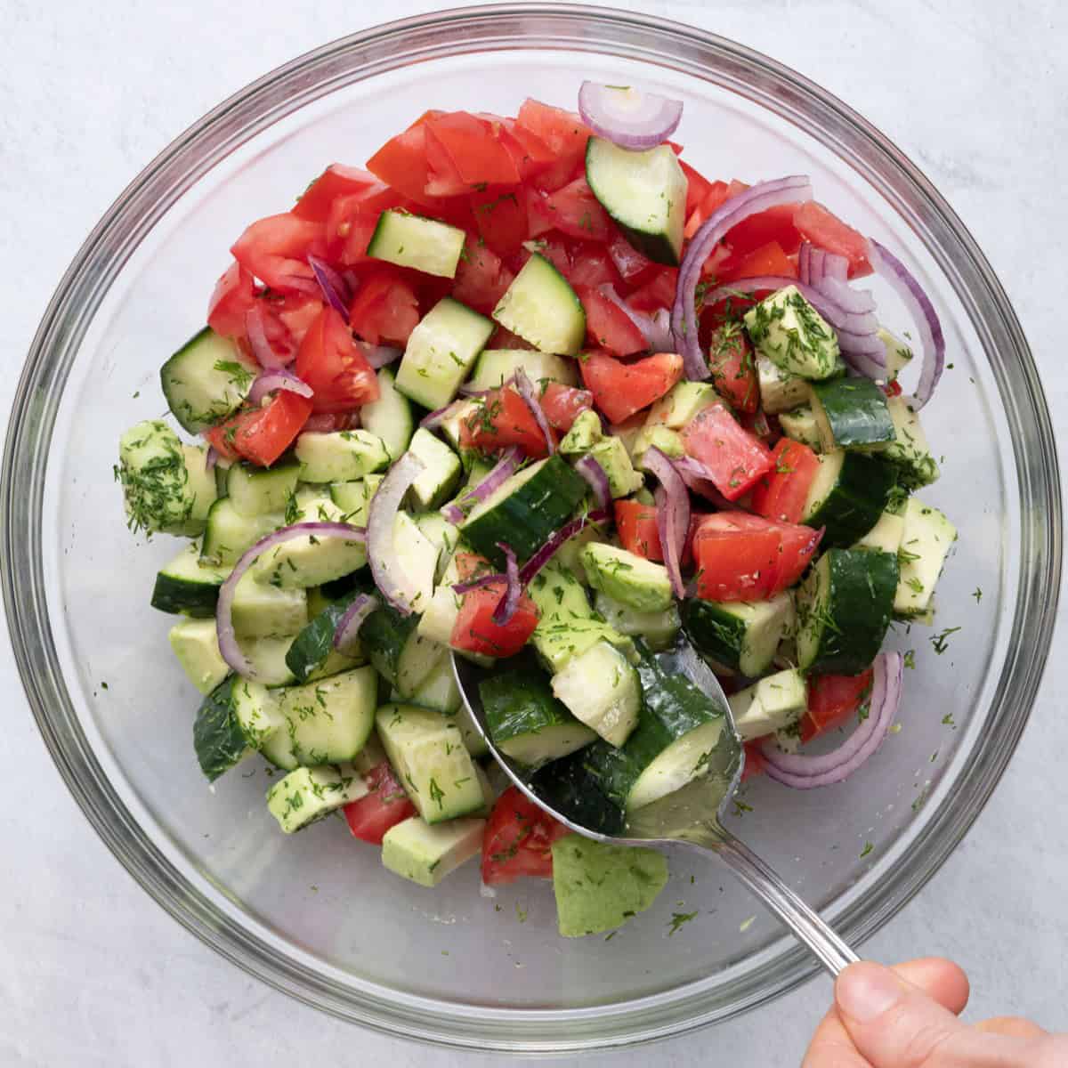 Tossing salad together with dressing.