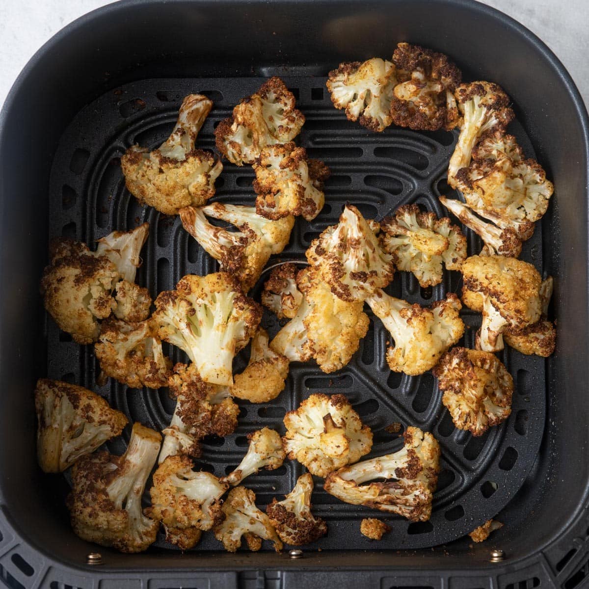 Cauliflower in basket after cooked to show crisp browned edges.