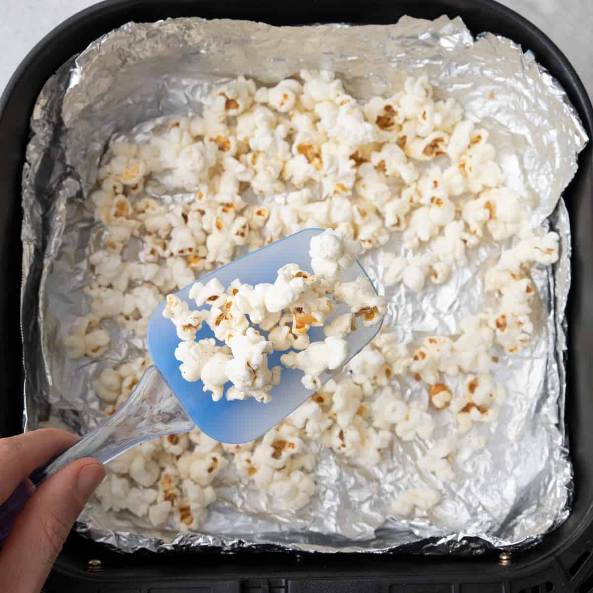 Remaining popcorn in basket after popping with spatula lifting some up.