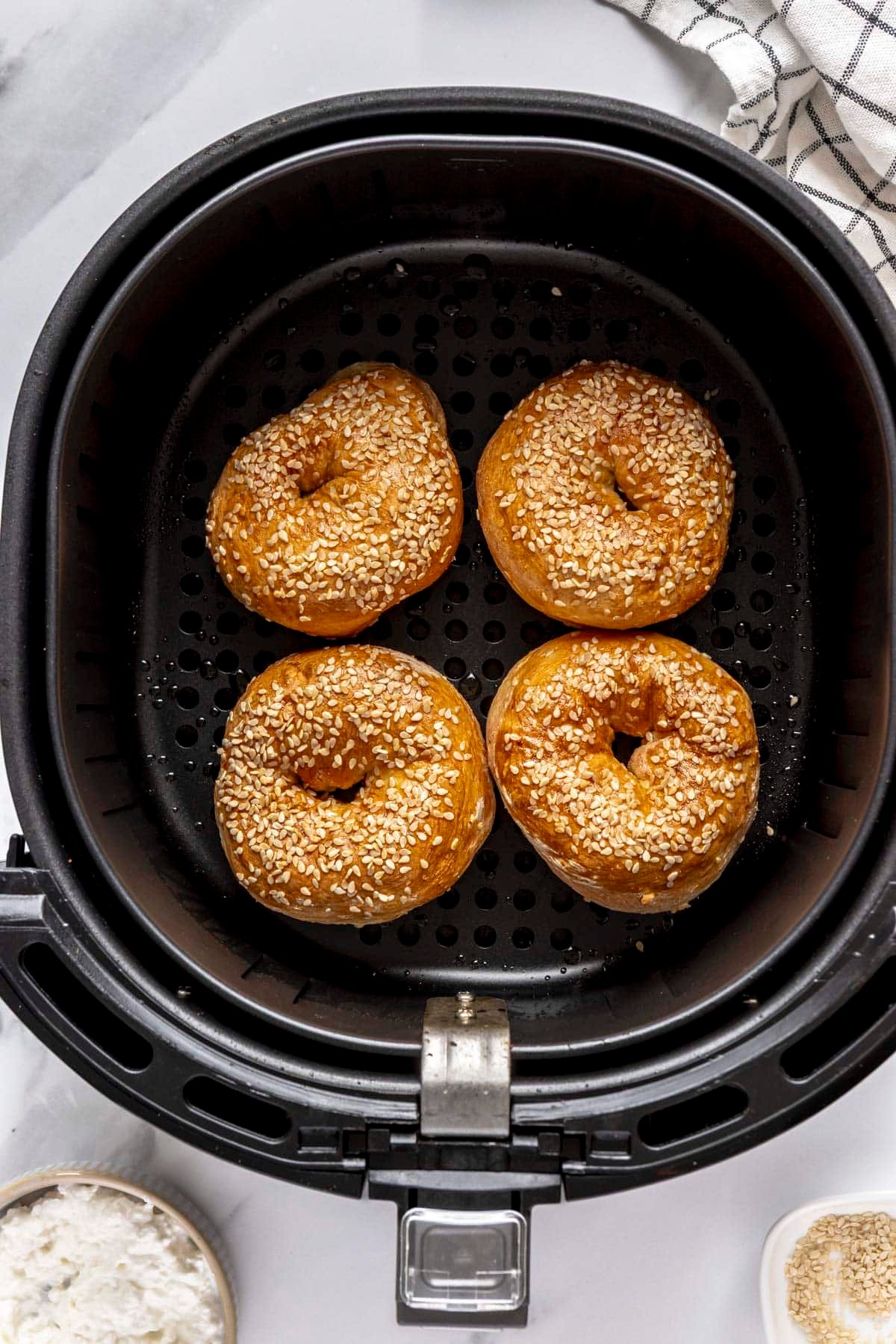 Cottage Cheese air fryer bagels with sesame seeds in an air fryer basket.