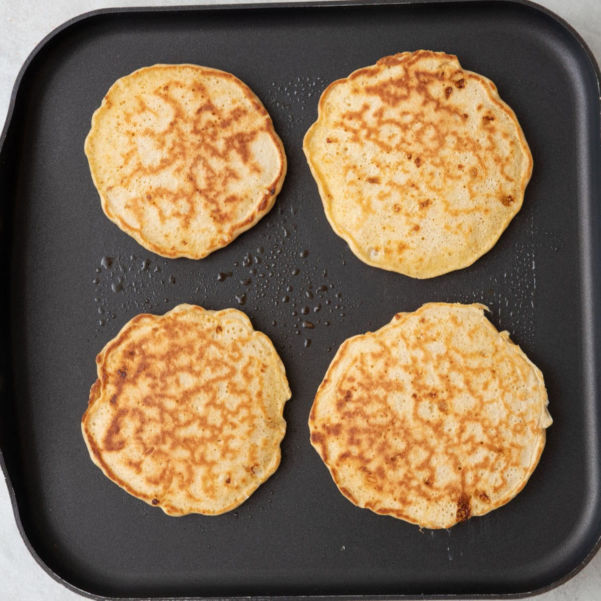 Pancakes after flipping on a griddle.