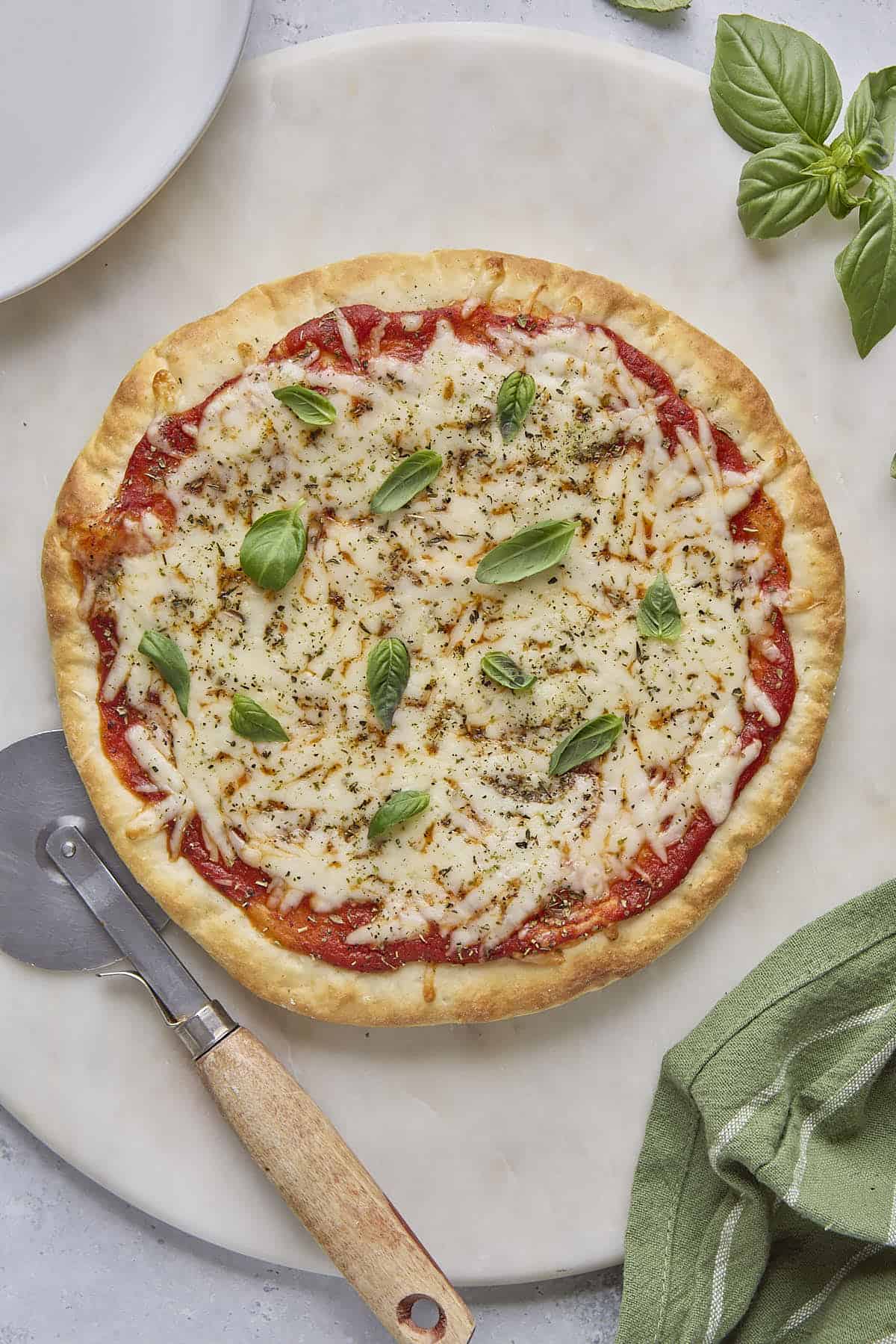Whole cottage cheese pizza on a round surface, garnish with fresh basil leaves.