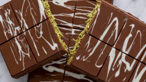 Two Dubai chocolate bars with one split in half to show green pistachio filling.