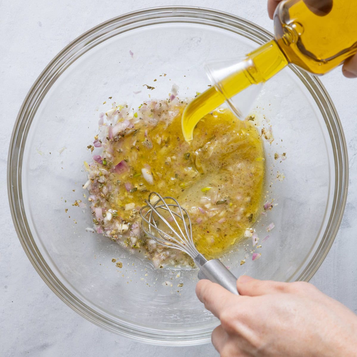 Whisking olive oil into dressing.