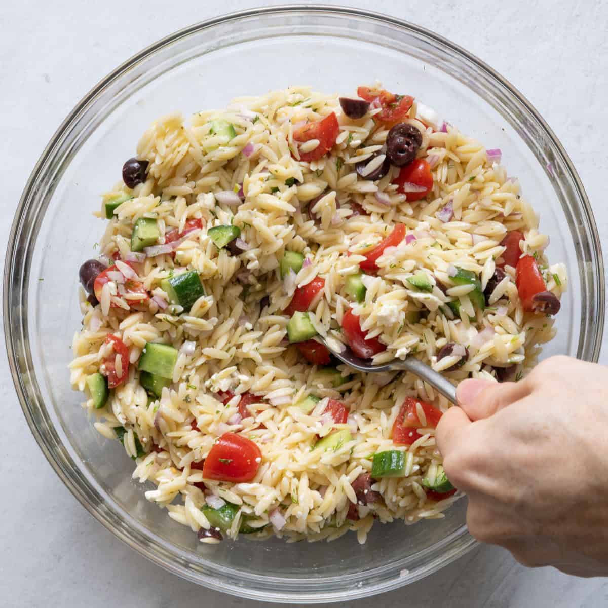 Tossing salad together with large spoon.