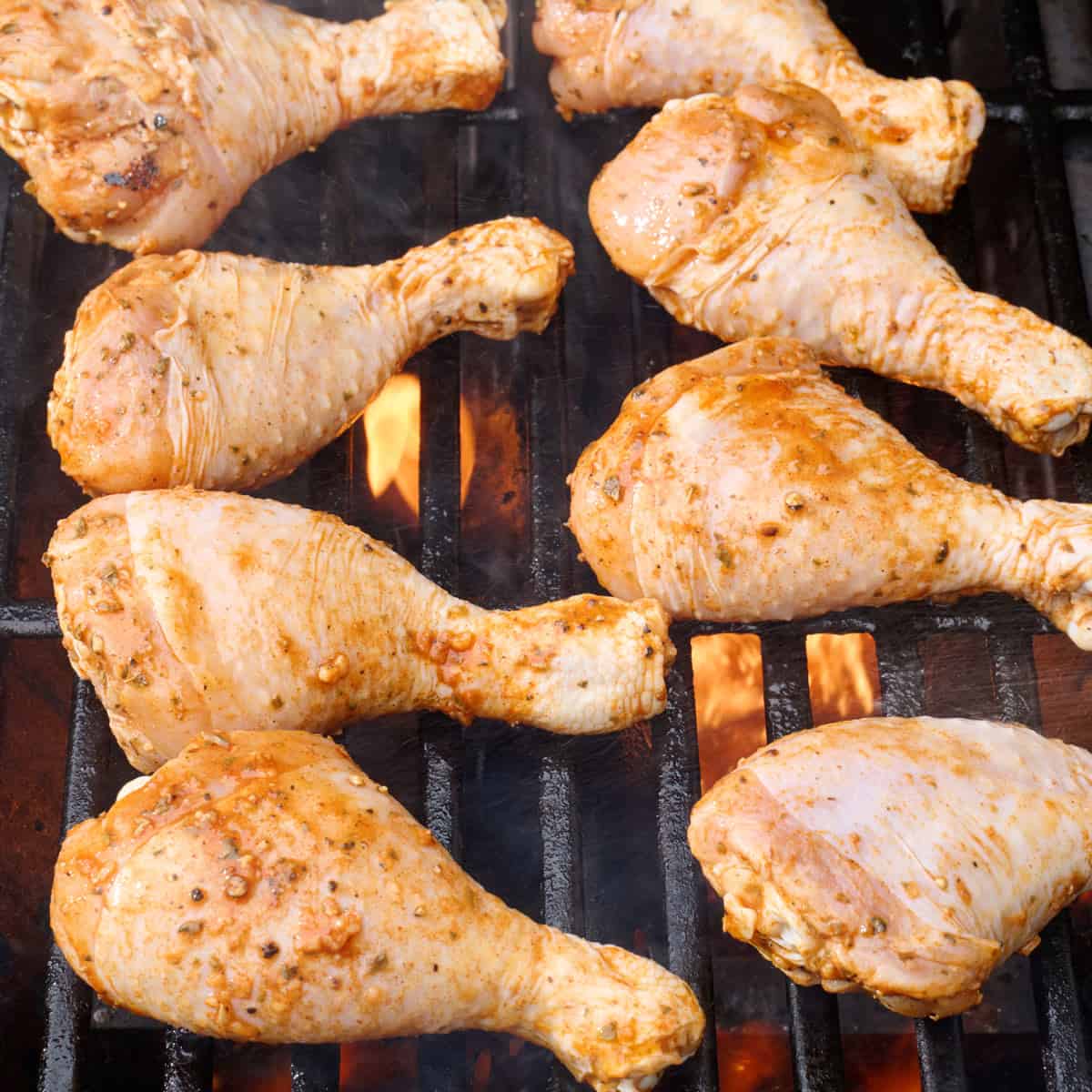 Marinated chicken legs on grill.