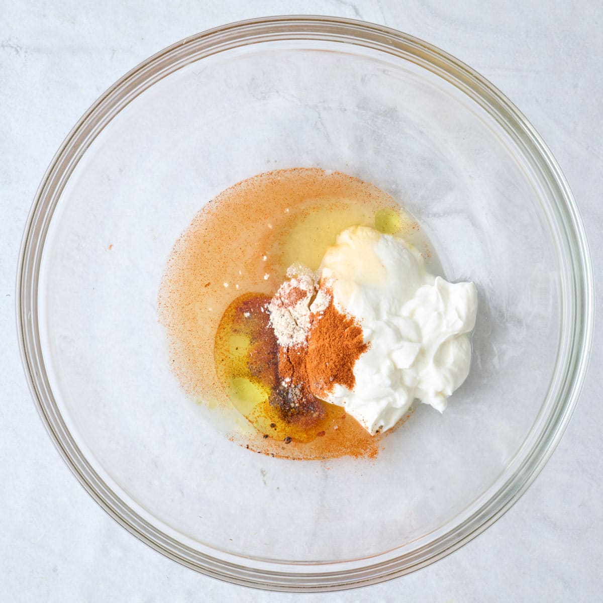 Yogurt, oil, juice, honey, and seasonings in a bowl before mixing.