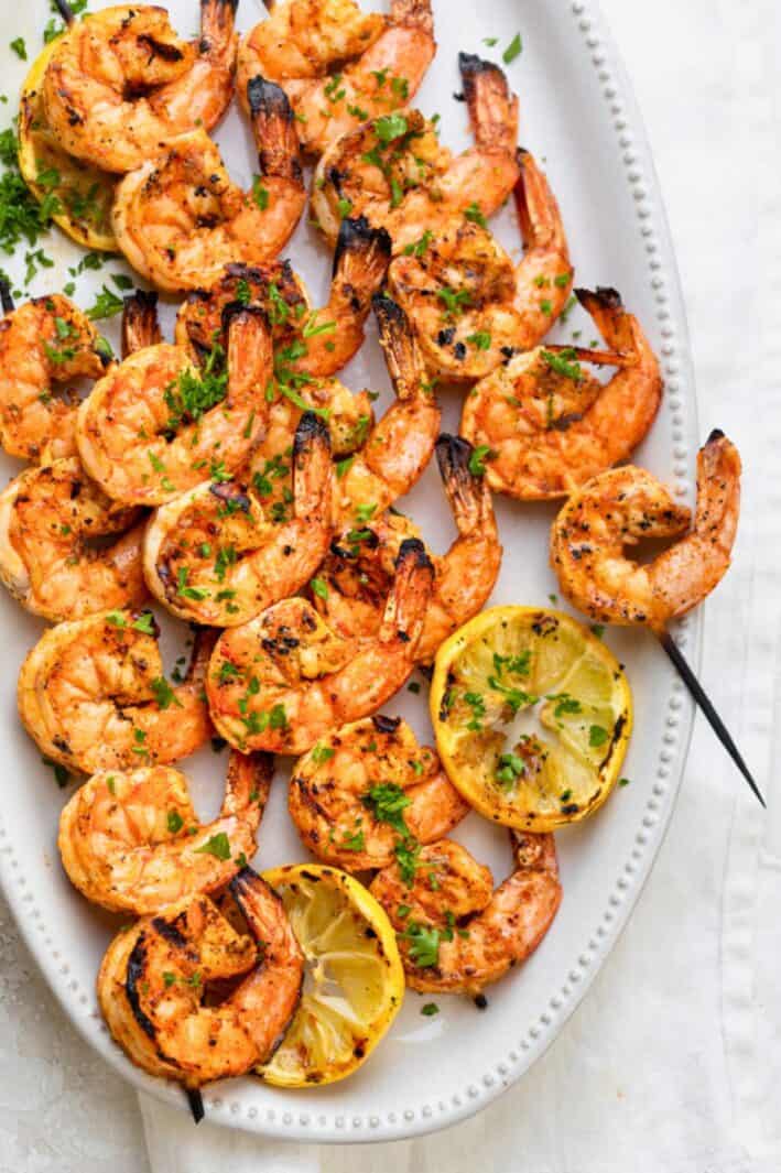 Easy grilled shrimp skewers on a plate with lemon slices.