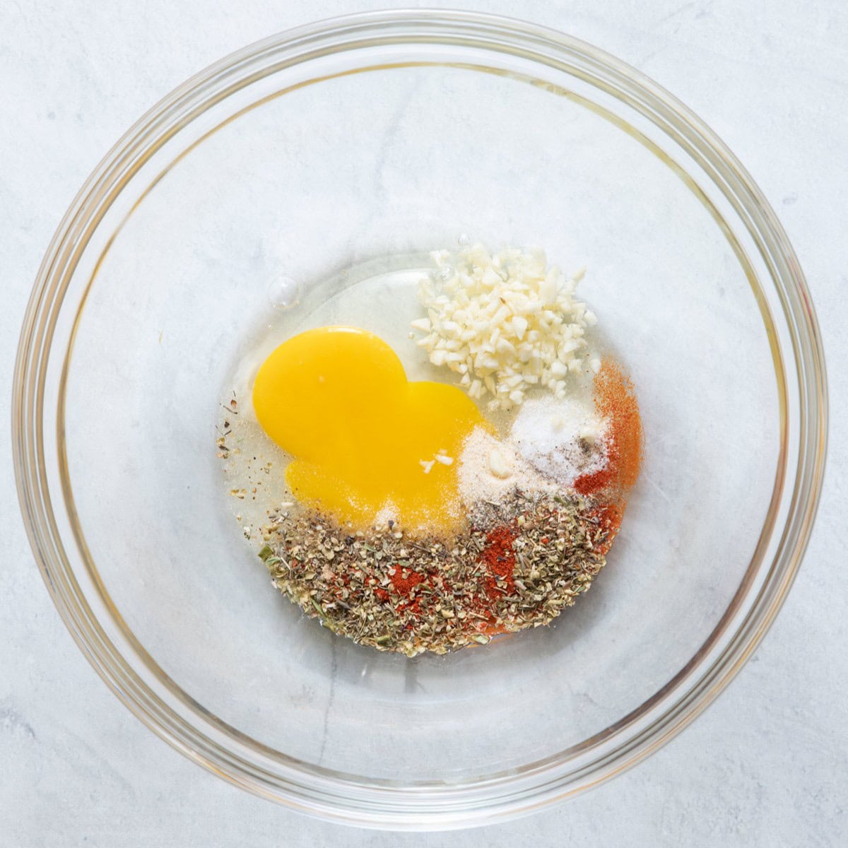 Egg, garlic, seasoning in bowl before mixed.