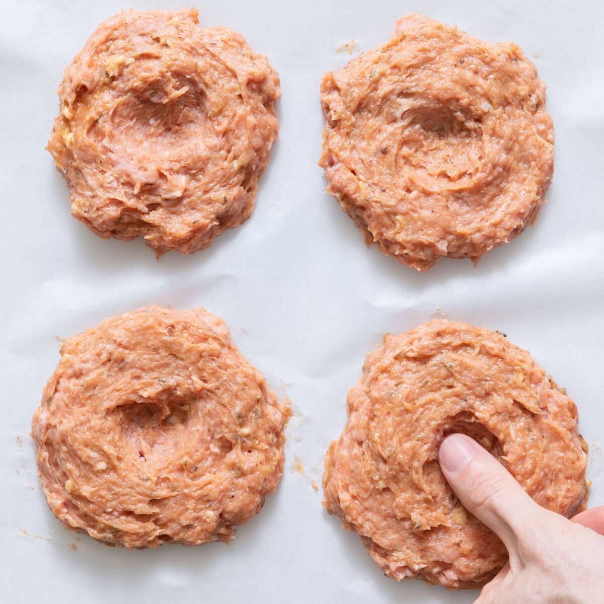 Using thumb to four indents into one of four patties on plate or parchment paper with .